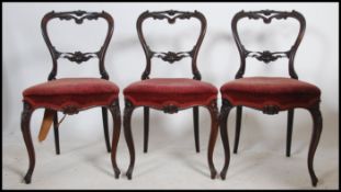 A set of 3 Victorian rosewood balloon back dining chairs being raised on cabriole legs with hoof