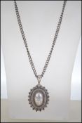 A late 19th century Victorian oval silver chase decorated mourning locket. Having hinged locket