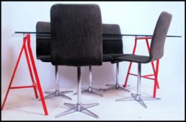 A retro red metal leg glass trestle dining table with glass top together with 4 black fabric