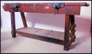 A mid 20th century Industrial workbench table being raised on angled end supports with lower tier