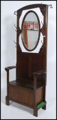 A good shaped 1930's oak hall stand settle having a bench seat with shaped elbow rests with swing