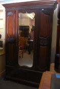 An Edwardian Art Nouveau mahogany wardrobe armoire raised on shaped bracket legs to the base with