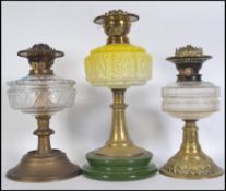 Three 19th/early 20th century brass oil lamps.  One has green ceramic base with yellow glass font