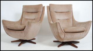 A good pair 1960's Parker Knoll batwing swivel armchairs being raised on a teak bases having