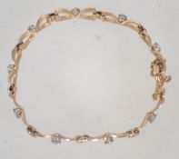 A hallmarked 9ct gold braclet having 9 bow shaped links and each bow being set with a pale blue