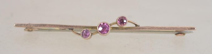 A 9ct gold bar brooch set with three pink stones with c clasp. Tests 9ct gold. Measures approx 3.