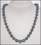 A hallmarked 18ct gold and black pearl necklace strung with knotted black pearls with an 18ct white