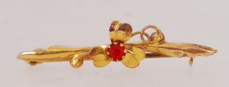 A 9ct gold bar brooch with 3 leaf clover motif set with central red stone with C clasp.
