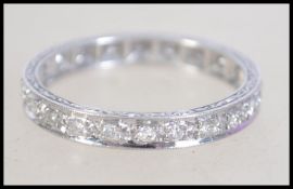 A platinum and diamond eternity ring with scroll side decoration,