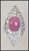 A ladies silver and cz cocktail dress ring adorned with a large garnet cabochon stone in an open