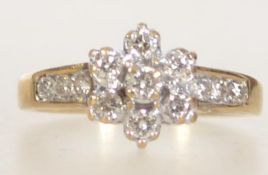 A 9ct gold and diamond ring with central diamond cluster and channel set diamond shoulders.