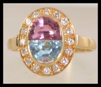 A hallmarked 18ct gold gold ring set with pink and aquamarine stone surrounded by a halo of