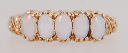 A 9ct gold 5 stone ring set with oval cut opals within a scroll gallery. Hallmarked London.