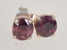 A pair of 9ct gold earrings set with dark red stones, one back base metal.