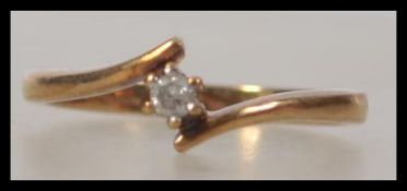 A 9ct gold 375 marked ladies diamond ring having single claw mounted stone to a cross over setting.