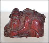 A Chinese carved amber style netsuke of a merchant