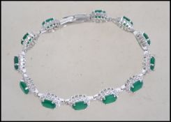 A silver CZ and faux emerald bracelet. The stones