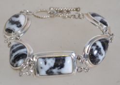 A silver 925 panel bracelet having oval, tear and rectangular shaped zebra agate panels and toggle