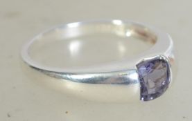 A silver 925 ladies dress ring having an inset princess cut purple stone. Weighs 4.3 grams size T