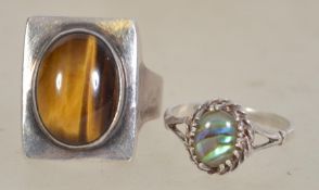 Two silver dress rings one with a central oval abalone cabochon in a prong setting marked silver.