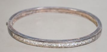 A silver 925 bangle bracelet of oval form having a line of inset clear stones and a safety catch.
