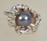 A silver 925 ladies dress ring having flower design with central black pearl. Weighs 7.5 grams