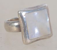 A silver 925 ladies dress ring having a mother of pearl square panel with silver border. Weighs 10.2