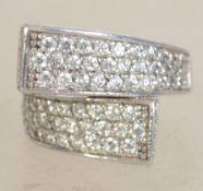 A silver 925 ladies dress ring of crossover form being adorned with rows of white paste stones.