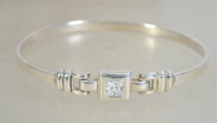 A silver 925 bangle bracelet with belt buckle design having central clear stone and hidden clasp.