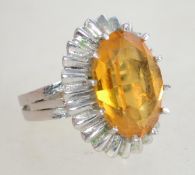 A large silver 1970s citrine cocktail ring having a large raised faceted citrine stone in a prong