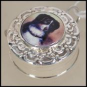 A silver novelty tape measure with embossed case and enamel pictorial image of a dog. 3cms long