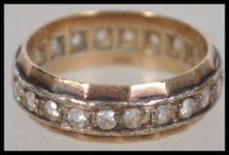 A 9ct gold eternity ring having a band of diamonds and sloped edges. Marked 9ct to the interior, all