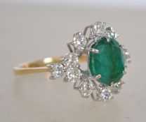 An 18ct gold, diamond and emerald cluster ring. The large central oval cut emerald approx 1.75cts