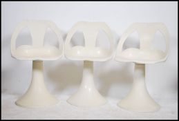 A set of retro 20th century white bar stools raised on tulip style bases with shaped and pierced