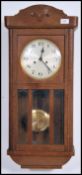 A 1920's oak wall clock having silvered dial with faceted hands over pendulum window. The case