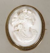 A cameo brooch, the oval carved shell cameo depicting a religious scene mounted within a scroll gold