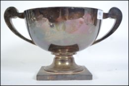 A large Edwardian silver hallmarked  twin handled trophy cup raised on a square pedestal base having