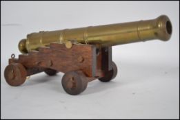 A decorative mid century desk top cannon raised on oak wooden plinth having brass cannon affixed