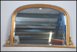 A large antique Victorian style gilt wall overmantel mirror of rococo form having shaped and