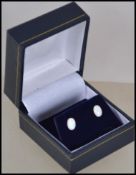 A pair of ladies silver and opal stud earrings complete in the presentation case. The opals of