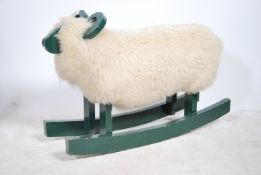 A retro mid century rocking sheep constructed of wood being green painted with wool upholstered