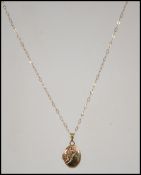A yellow metal (tests as 9ct gold) locket pendant with chased decoration with a 9ct gold chain