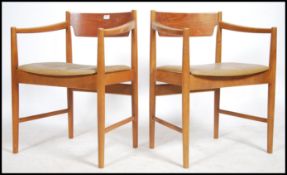 A pair of Danish inspired mid century teak wood carver armchairs. The teak show wood frames with