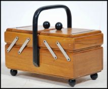 A vintage retro 20th century metamorphic sewing work box with an ebonised handle atop.