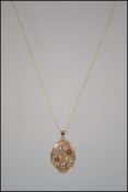 A 9ct gold locket and necklace pendant set to a fine linked chain , the oval locket adorned with
