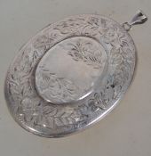 A large silver rococo locket having floral carouche to centre ( plain ) with bale atop. London