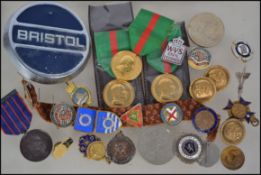 A collection of vintage medals and enamel badges etc to include a Bristol car badge, military enamel