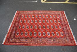 A large good quality Afghan floor rug having a geometric pattern on a Russet Red ground.