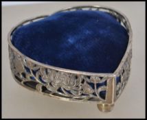 A Chinese silver pin cushion in the form of a heart. The lattice worked body with ball feet marked