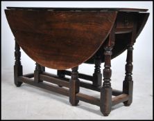An 18th century country oak drop leaf / gate leg dining table being raised on turned legs with pad